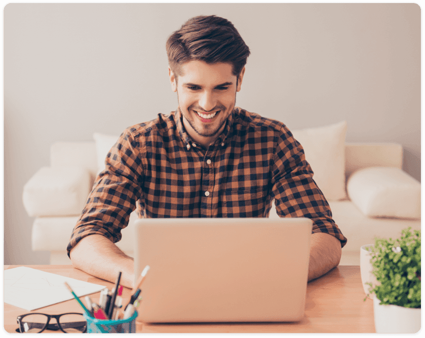 Homem jovem com uma camisa xadrez sorrindo enquanto usa a Hallco para fazer cotação e compra dos seus materiais de construção para sua obra